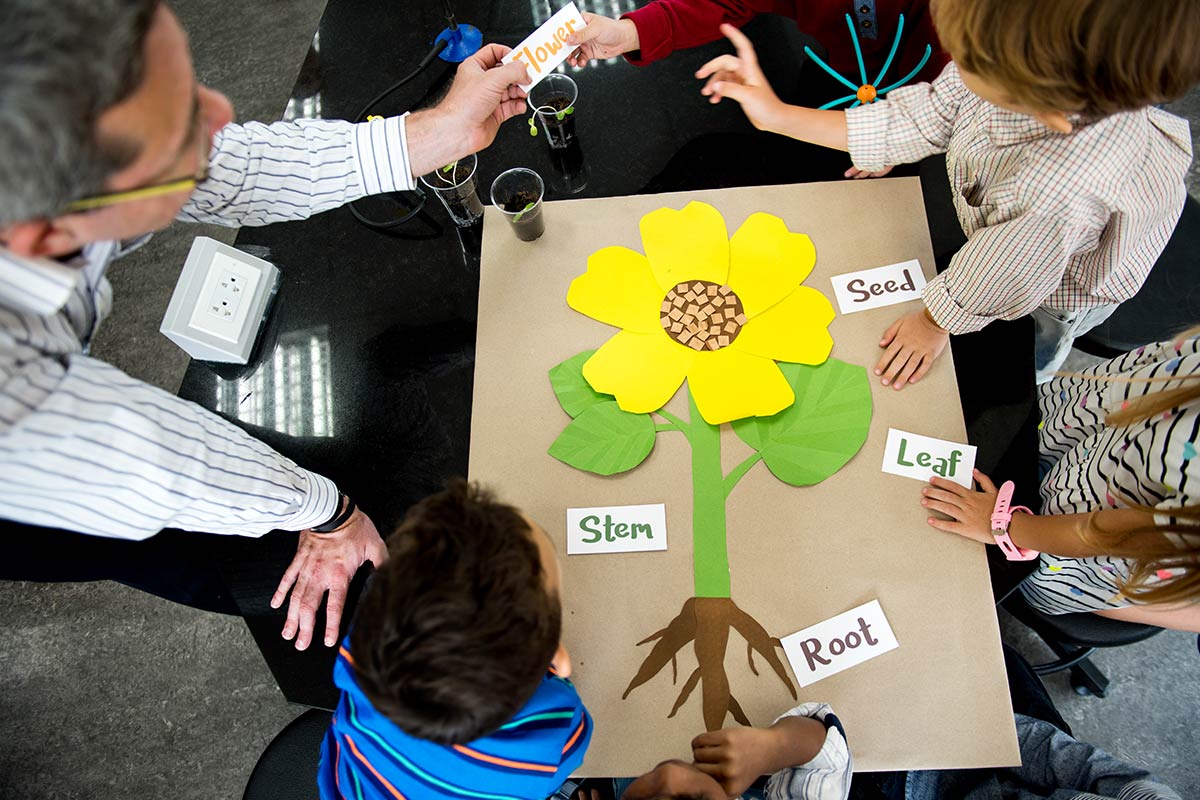 Teacher teaching flower structure to diverse group